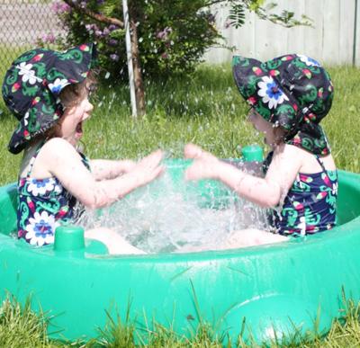 Two-year-old Twins splashing each other in the pool.